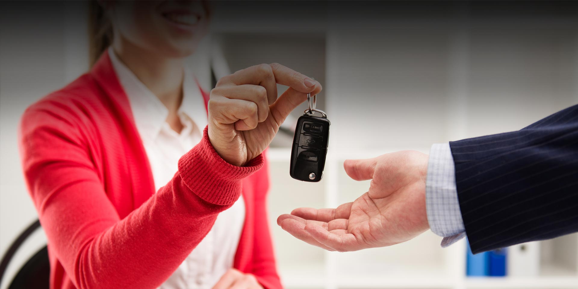Salesperson handing over car keys to a new car buyer